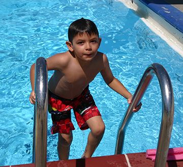 Child exiting pool on pool ladder.