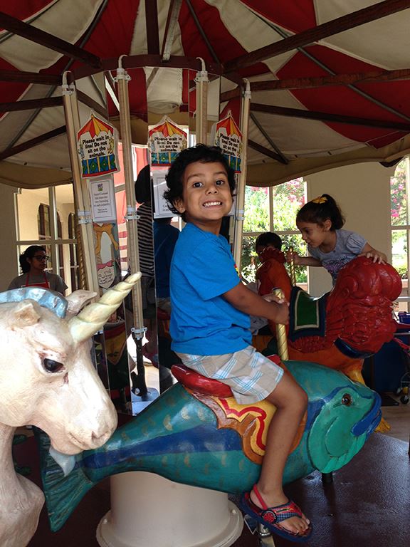 Child on Childrens Museum merry-go-round at Itty Bitty Camp